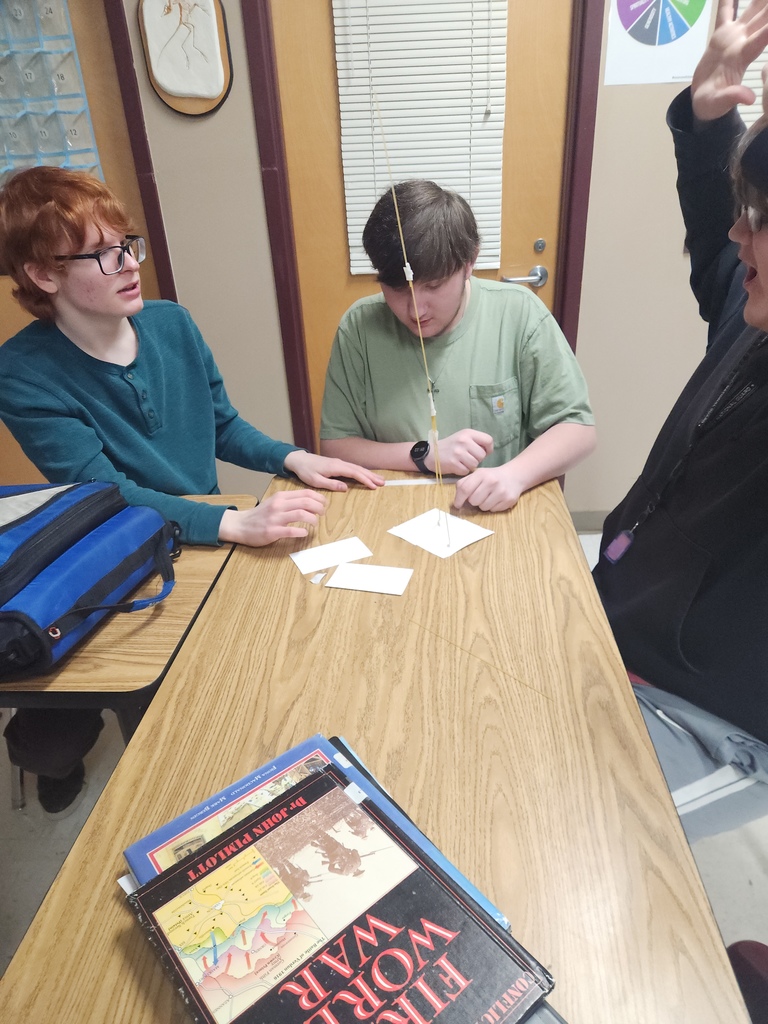 A group of high school students who are gathered in a group building a STEAM activity.