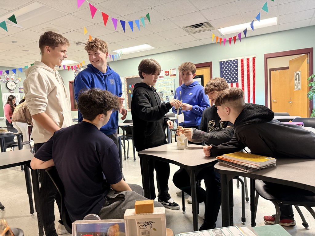 A group of high school students who are gathered in a group building a STEAM activity.
