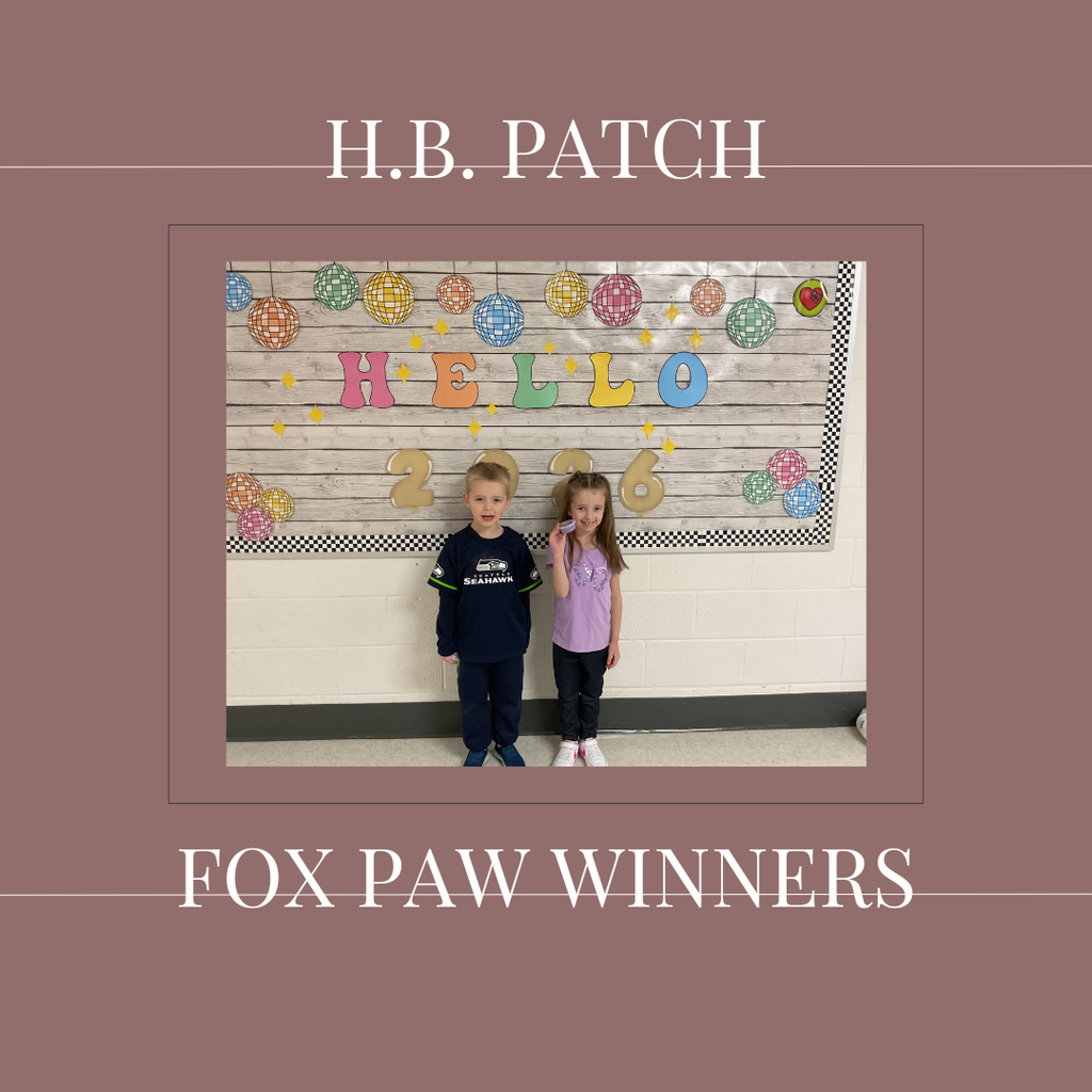 A couple of early elementary students standing in front of a bulletin board. 