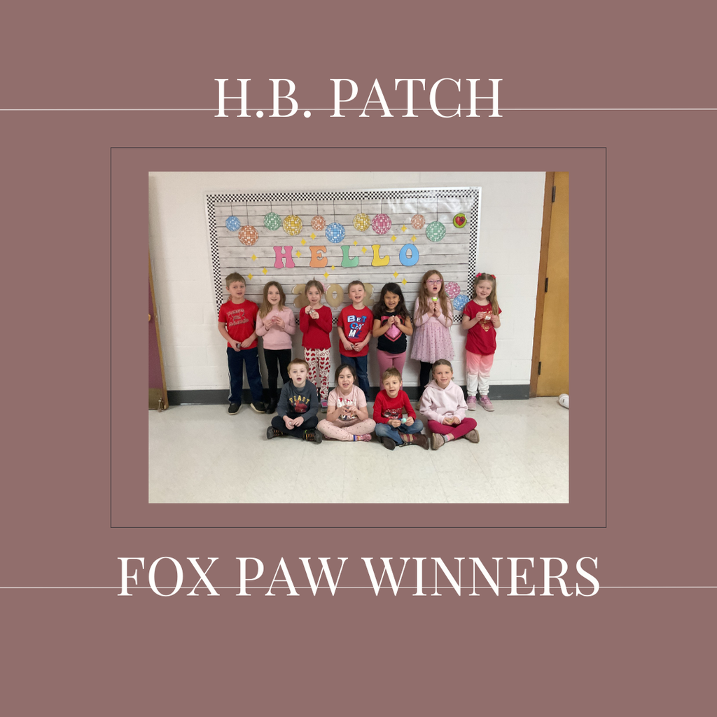 A group of early elementary students standing in front of a bulletin  board.