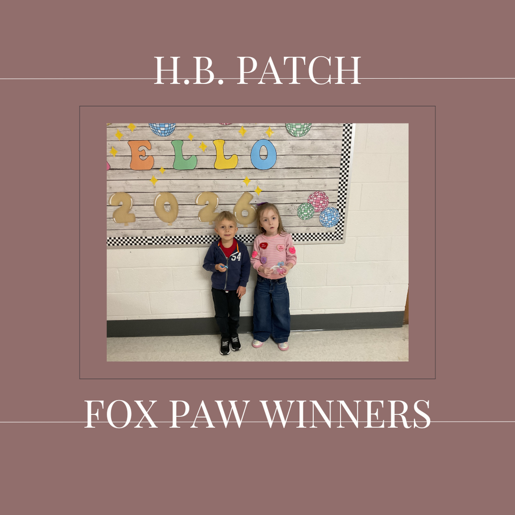 A couple of early elementary students standing in front of a bulletin board. 