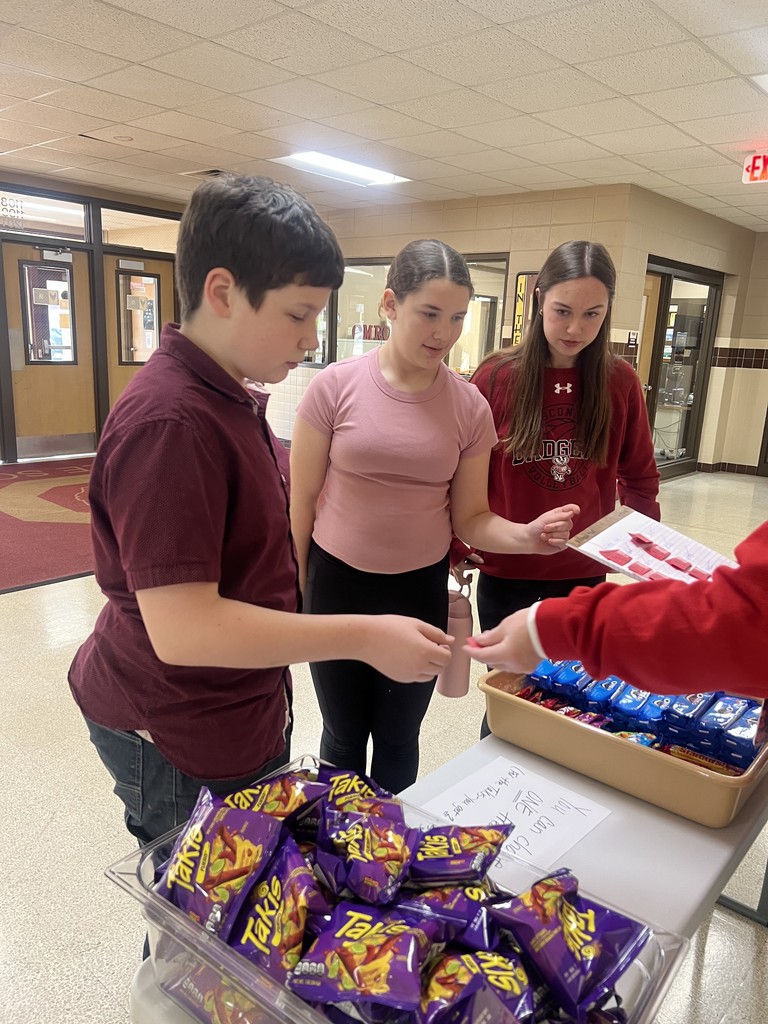 Three middle school students exchanging raffle tickets for treats.