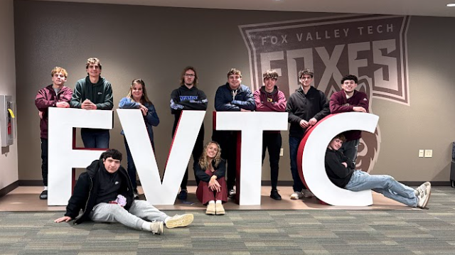 A group of high school students and thier teacher surrounding large FVTC letters.