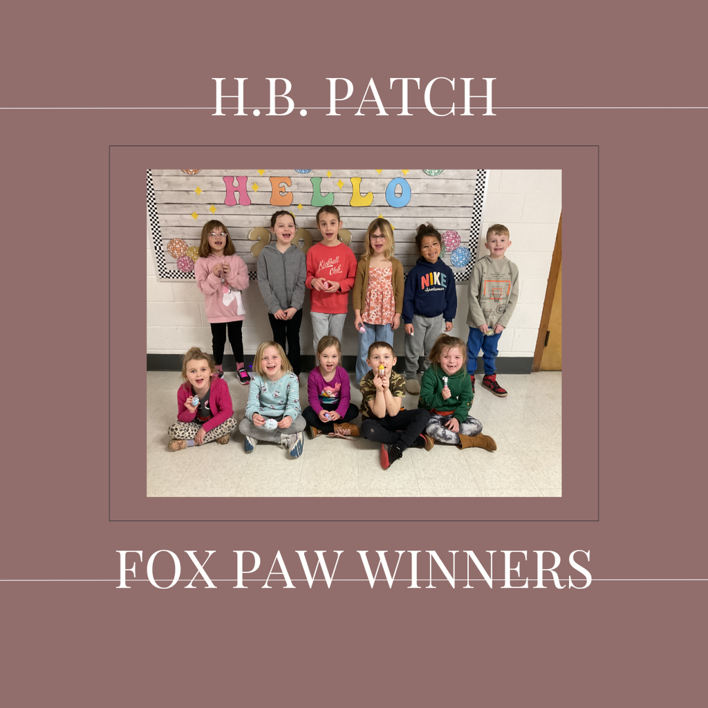 A group of early elementary students standing in front of a bulletin  board.