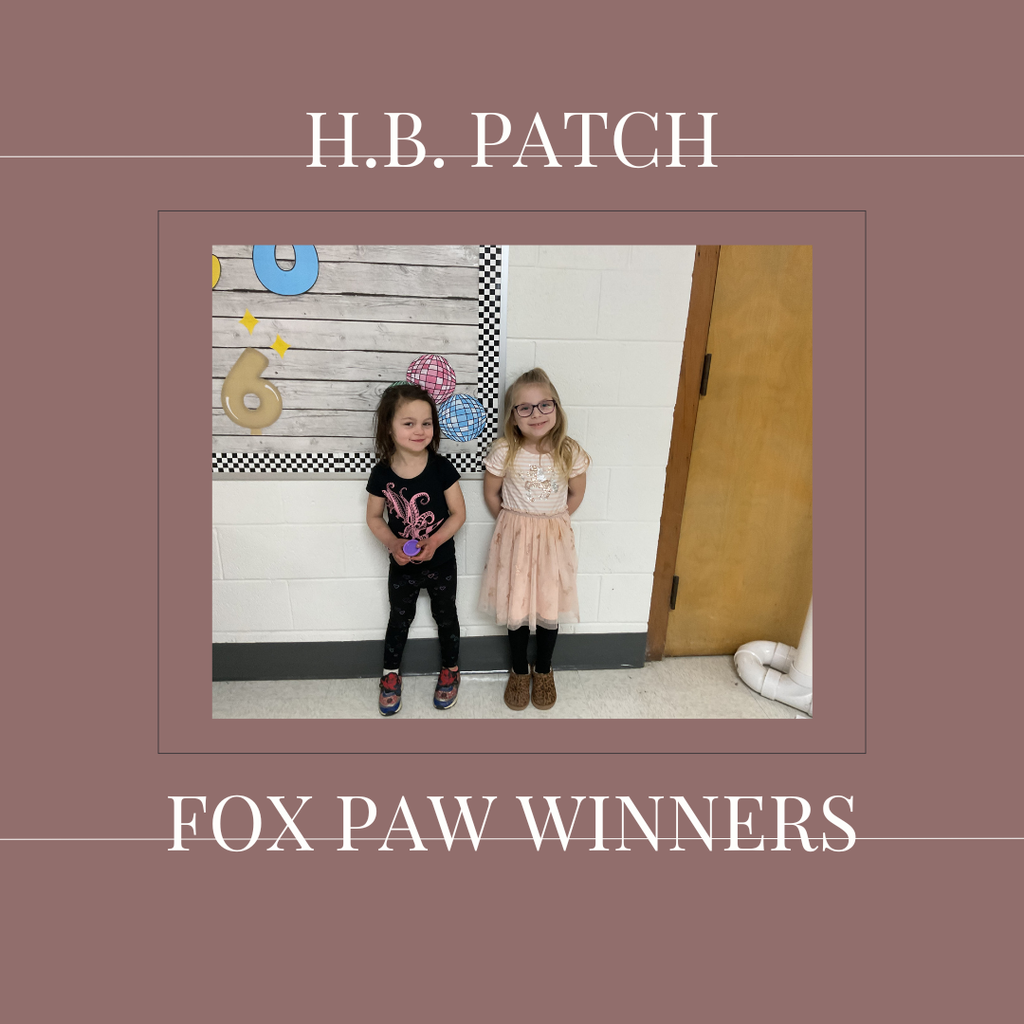 A couple of early elementary students standing in front of a bulletin board. 