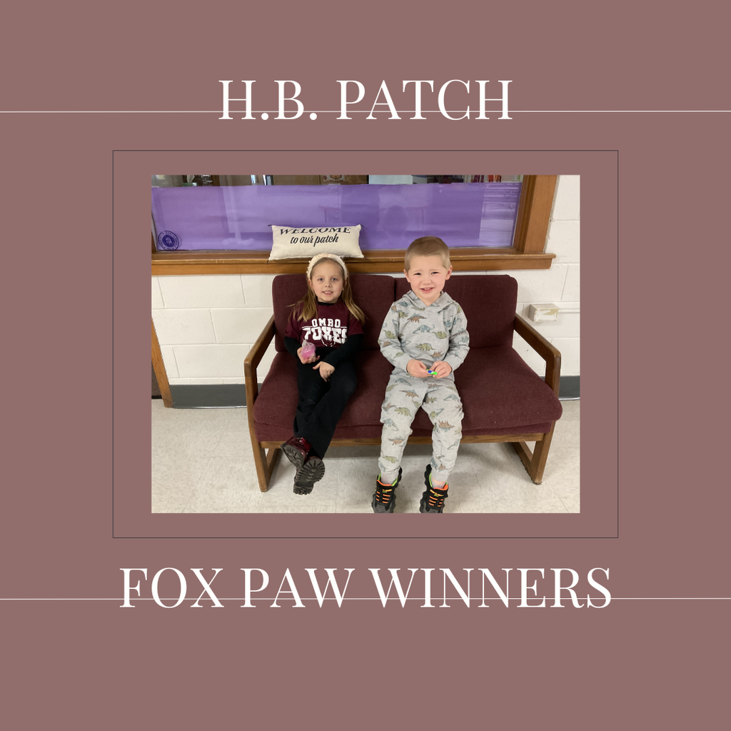 A couple of early elementary students standing in front of a bulletin board. 