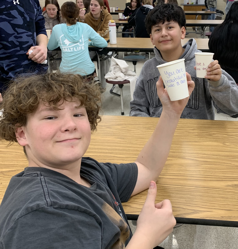 Two middle school boys holding up a cup with a positive message.