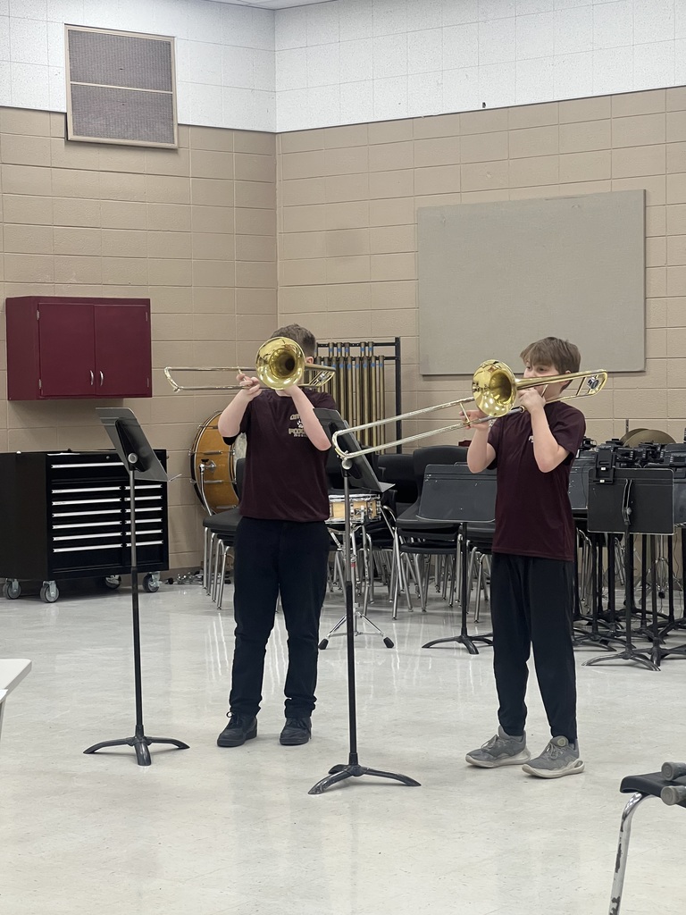 Two middle school students playing a trombone.