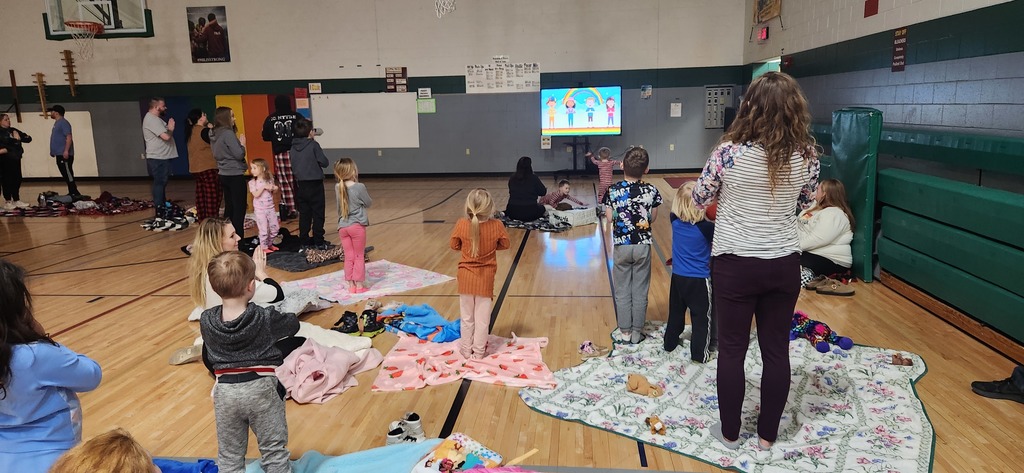 4K students and their families watching a yoga video in a gymnasium.