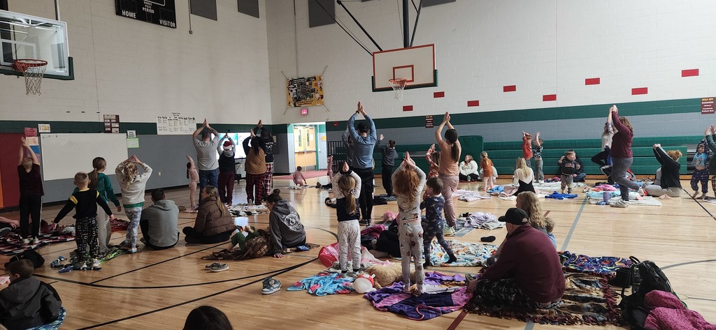4K students and their families watching a yoga video in a gymnasium.
