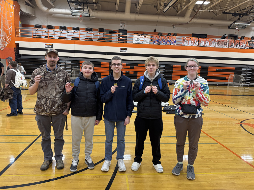 Five high school students standing in a line holding a medal they earned in front of them.