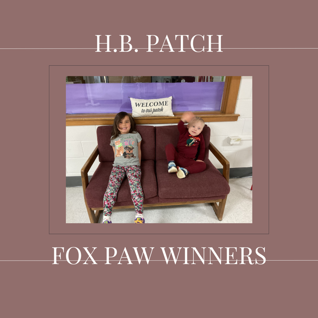 A couple of early elementary students standing in front of a bulletin board. 