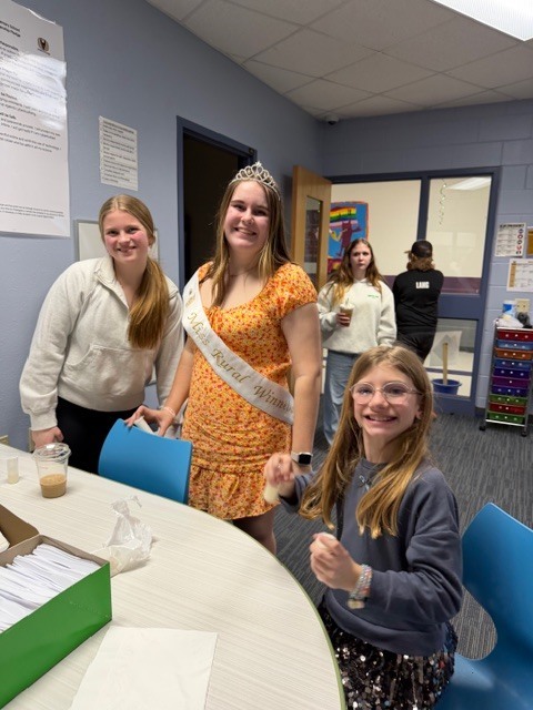 Three individuals posing together at a table. 
