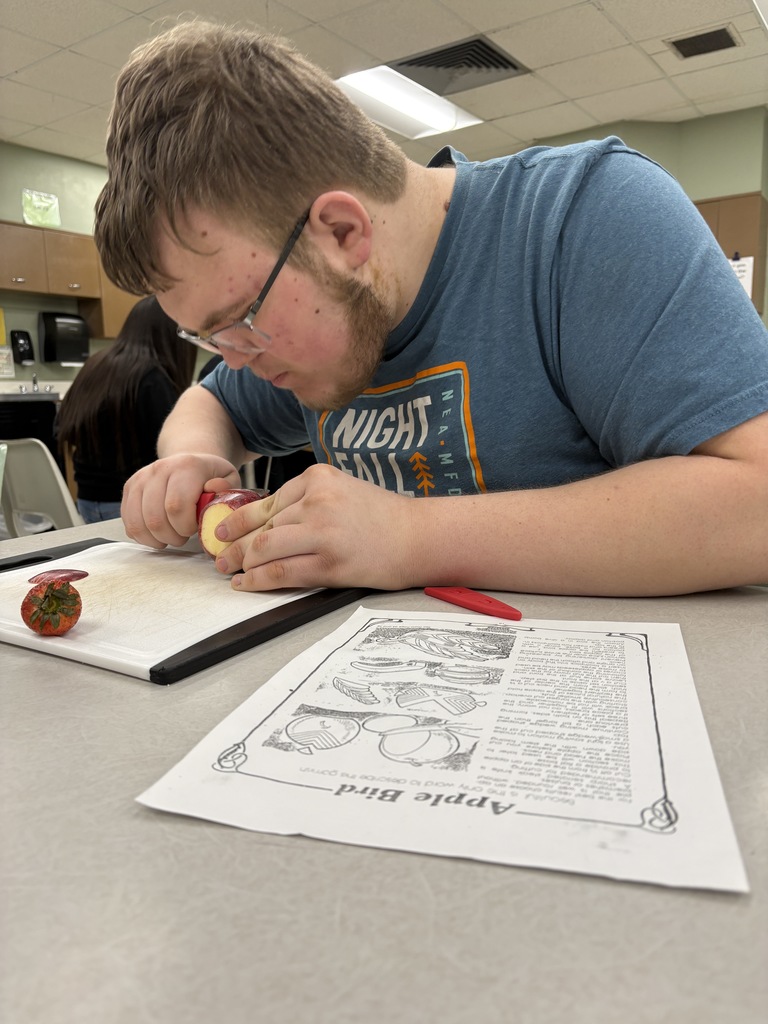 High school student working with a paring knife on an apple. 