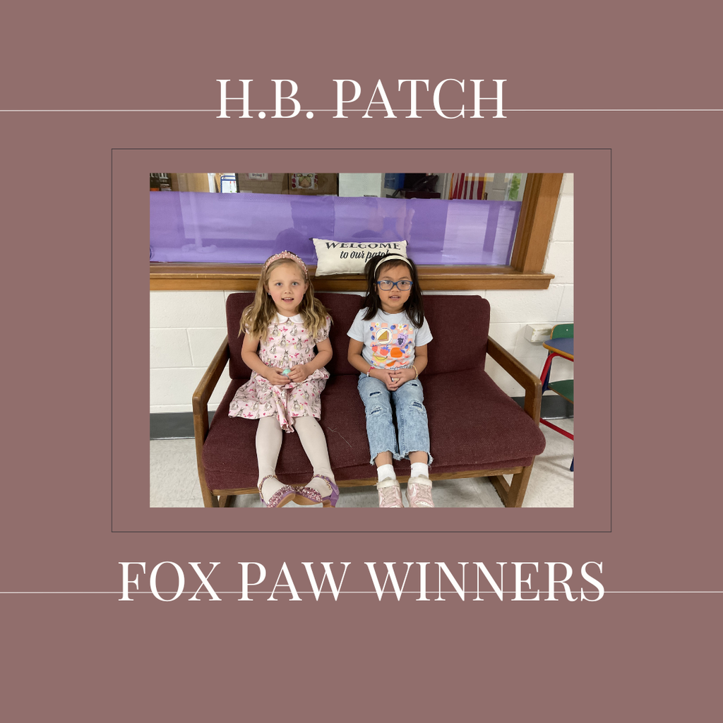 A couple of early elementary students standing in front of a bulletin board. 