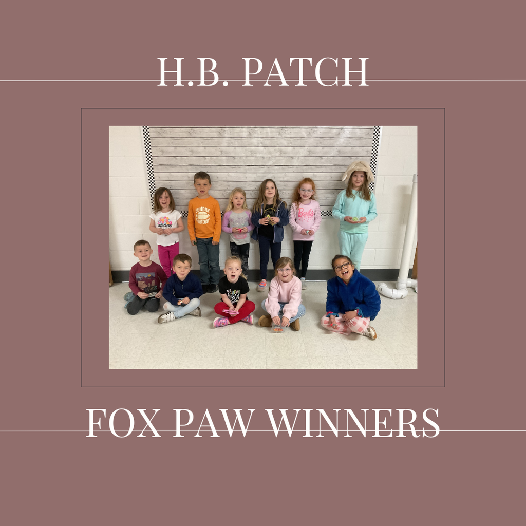 A group of early elementary students standing in front of a bulletin  board.