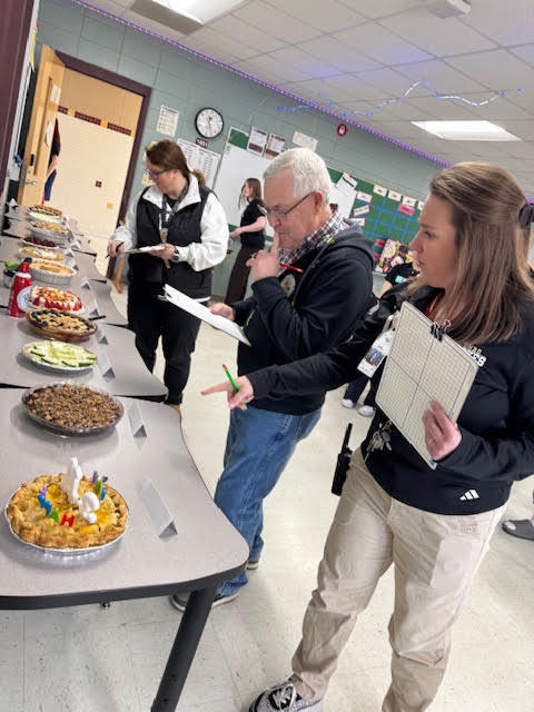 Faculty judging pies on a table.