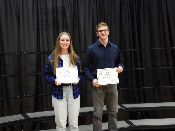 Two students holding certificates in front of them.
