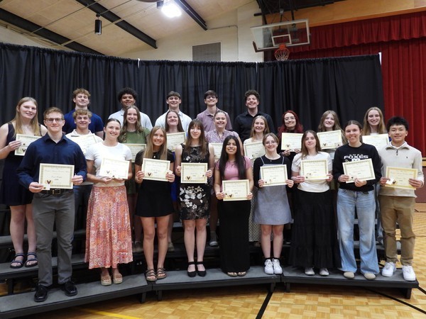 A group of students standing on risers holding certificates in front of them.
