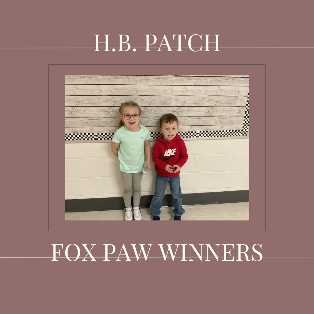 A couple of early elementary students standing in front of a bulletin board. 