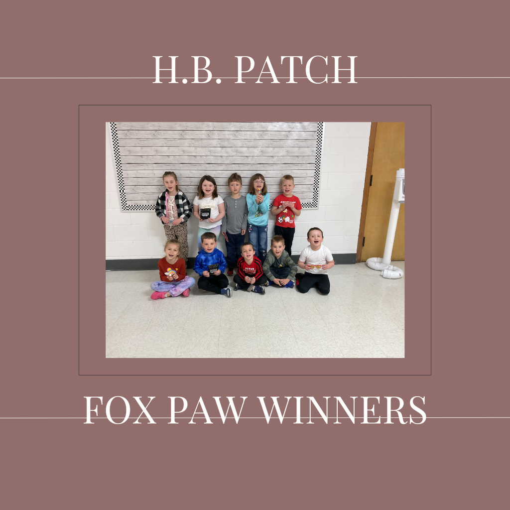 A group of early elementary students standing in front of a bulletin  board.
