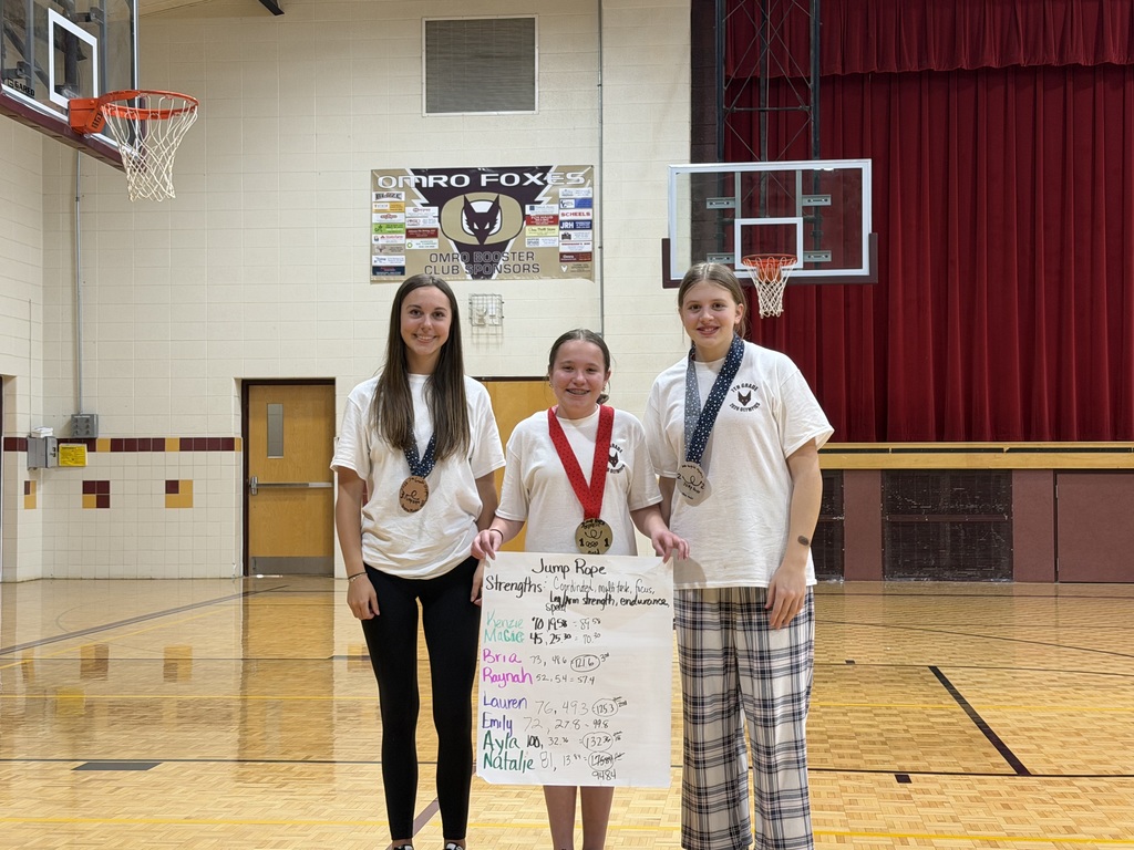 Three middle school students, standing, holding a poster and a medal.