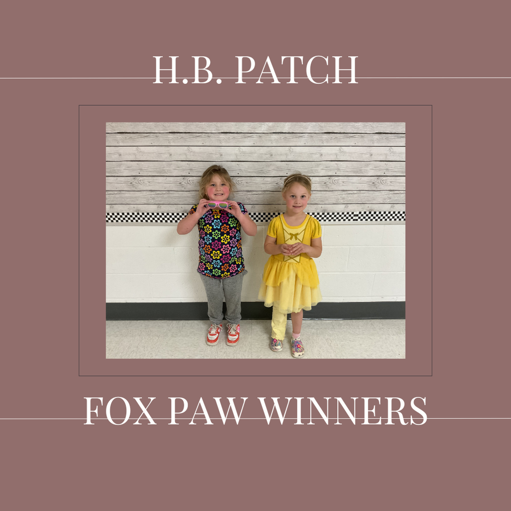 A couple of early elementary students standing in front of a bulletin board. 