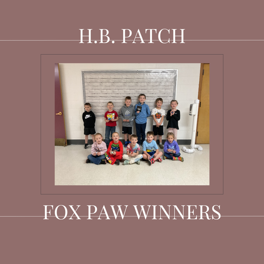 A group of early elementary students standing in front of a bulletin  board.