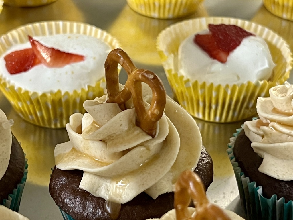 Cupcake with a pretzel on top and two desserts behind it.