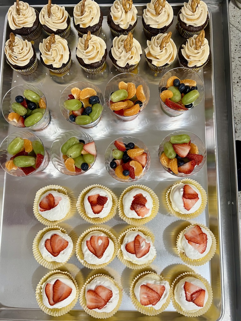 Tray of desserts that include a fruit cup, cupcake and strawberry dessert.