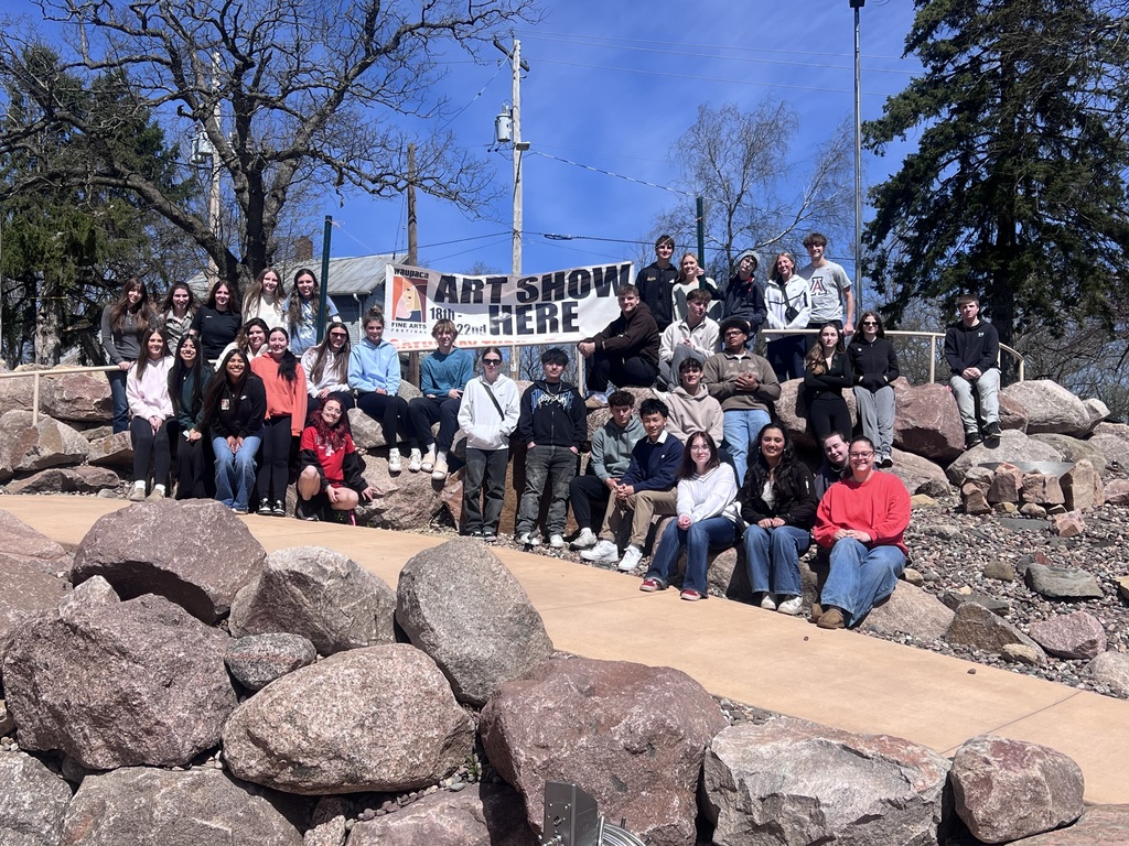 A group of high school students around a banner that says Art Show Here.