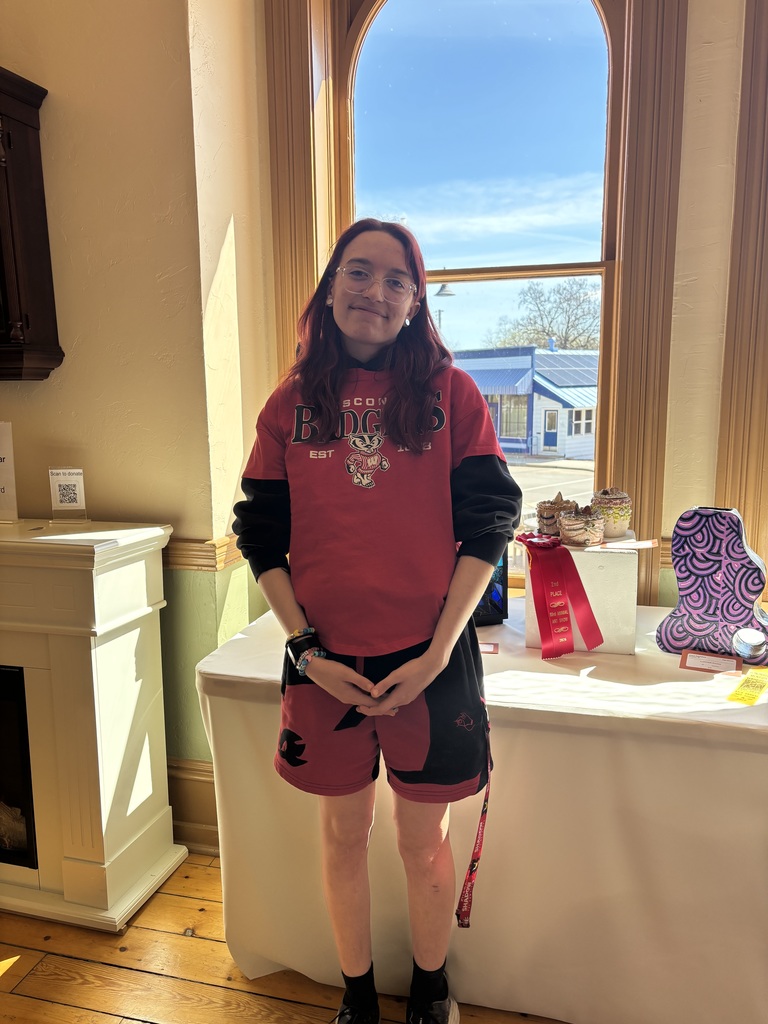 A picture of a high school student by their art work. 