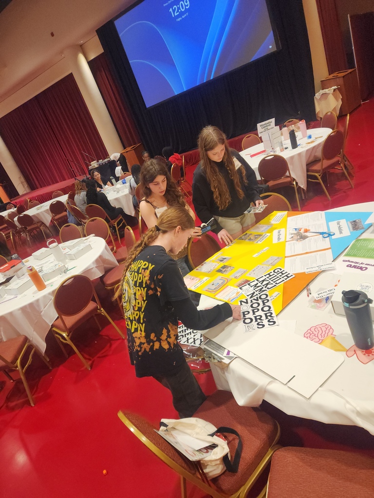 Three high school students putting together a poster presentation.