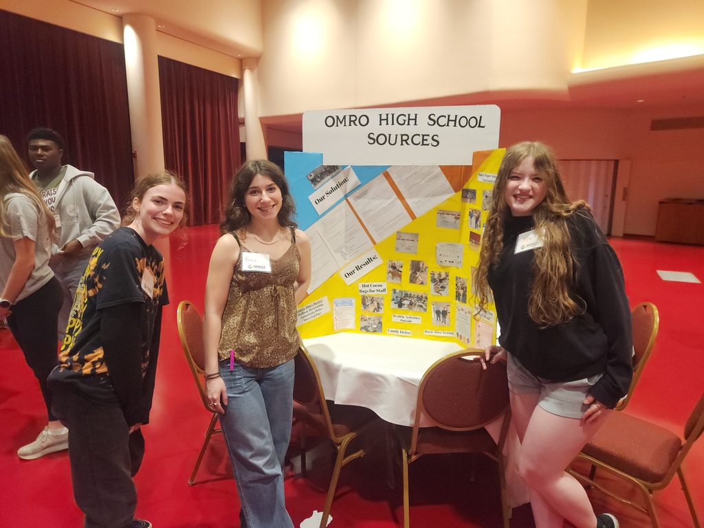 Three high school s tudents by a poster presentation.