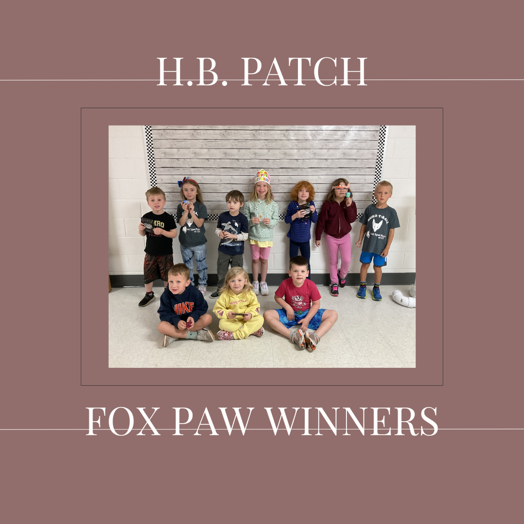 A group of early elementary students standing in front of a bulletin  board.