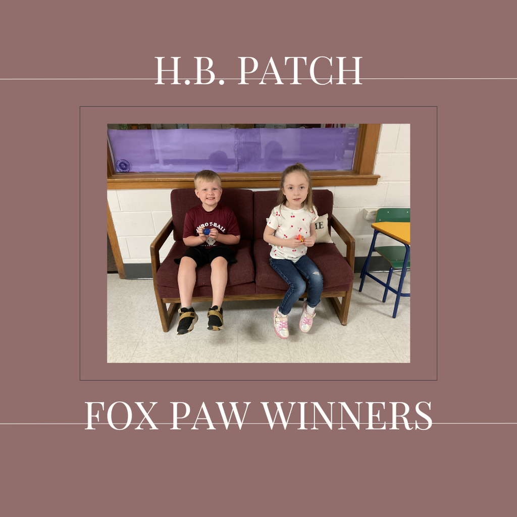 A couple of early elementary students standing in front of a bulletin board. 