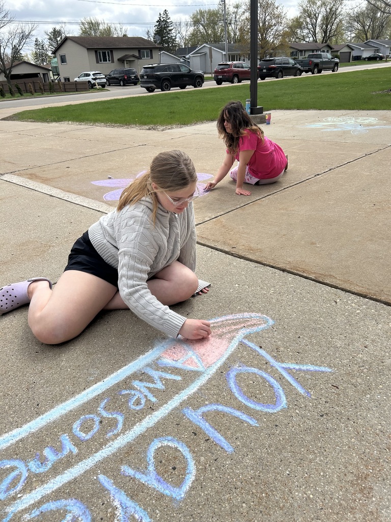 Two high school students drawing with sidewalk chalk.