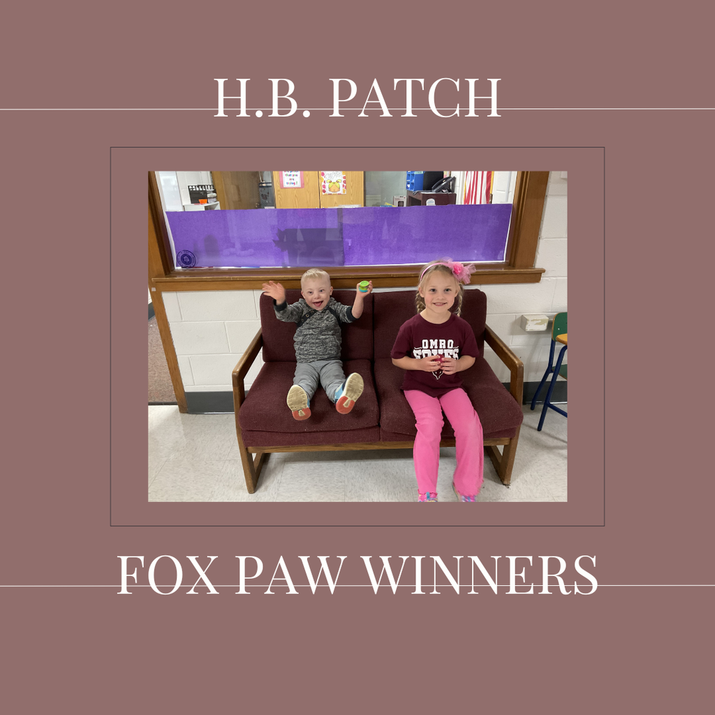 A couple of early elementary students standing in front of a bulletin board. 