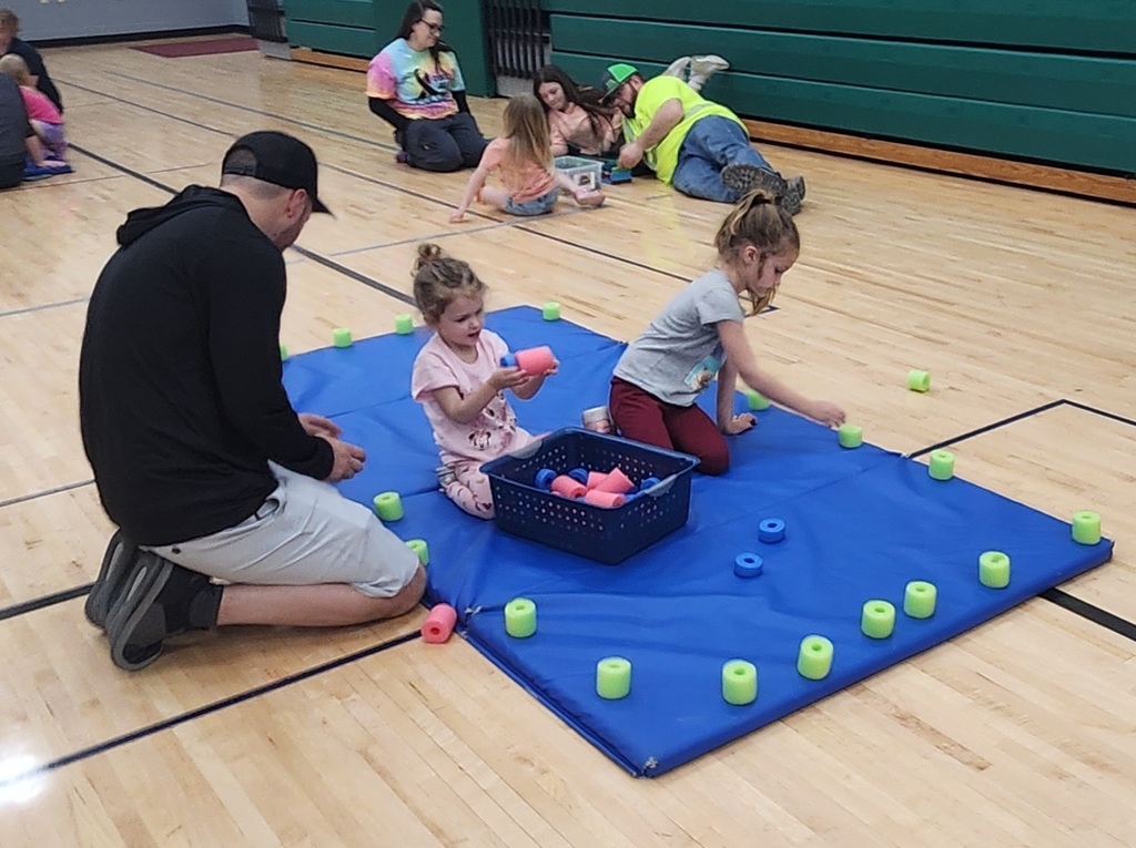 Families sitting on the floor together, building with blocks. 