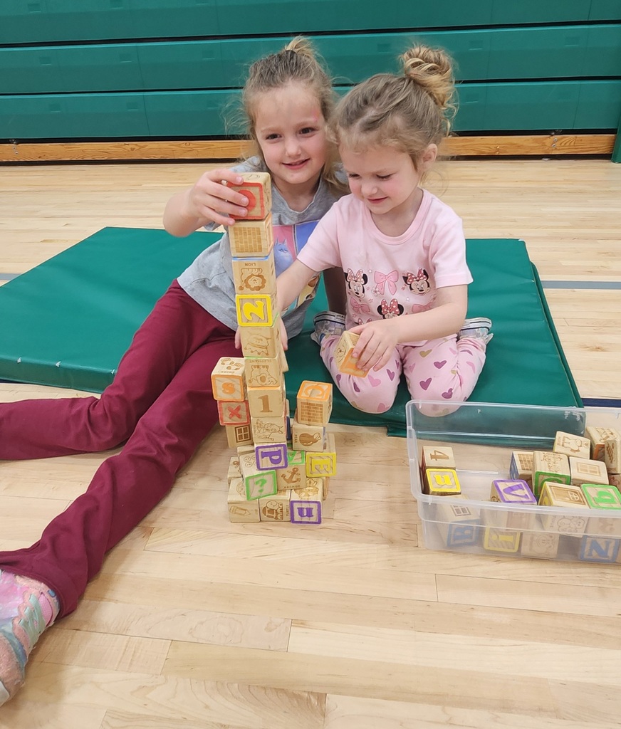 Two early elementary students sitting on the floor building with blocks. 