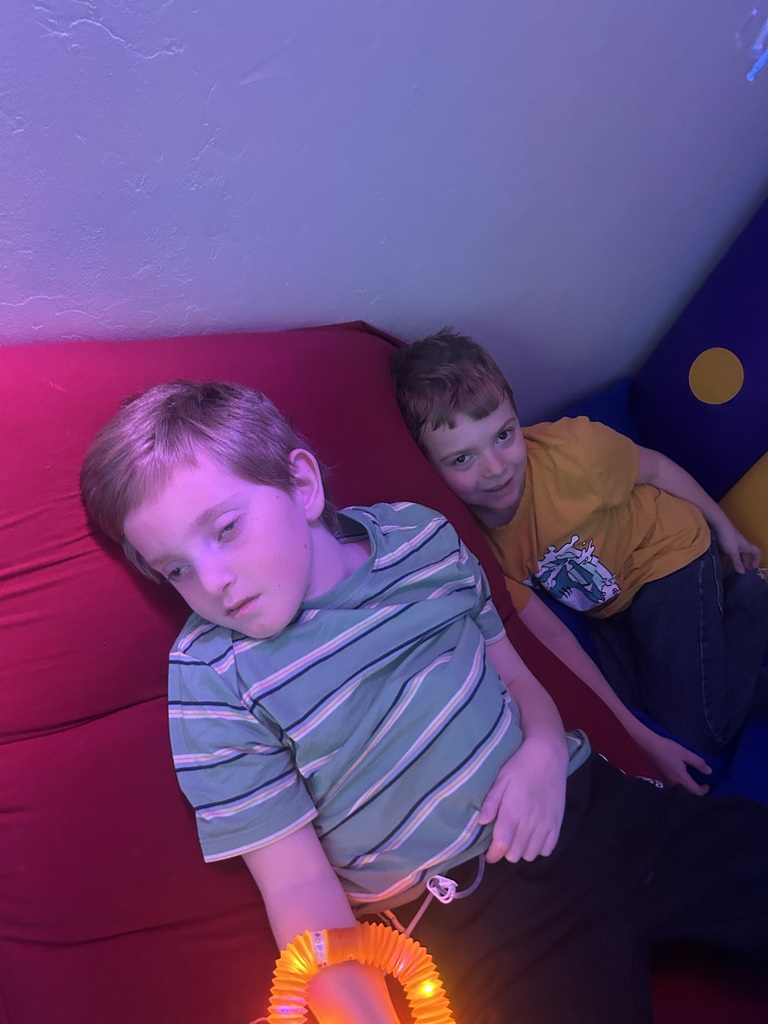 Two boys laying down in a dark room on pillows.