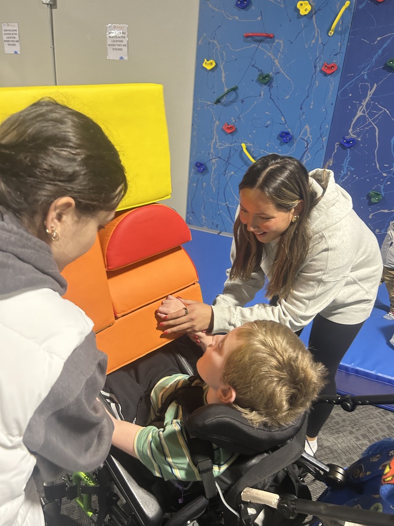 Two adults helping a young learner explore sensory objects.