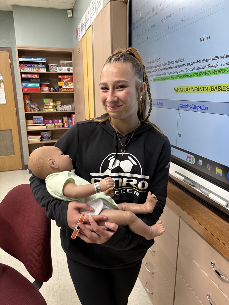 Middle school student holding a fake baby.
