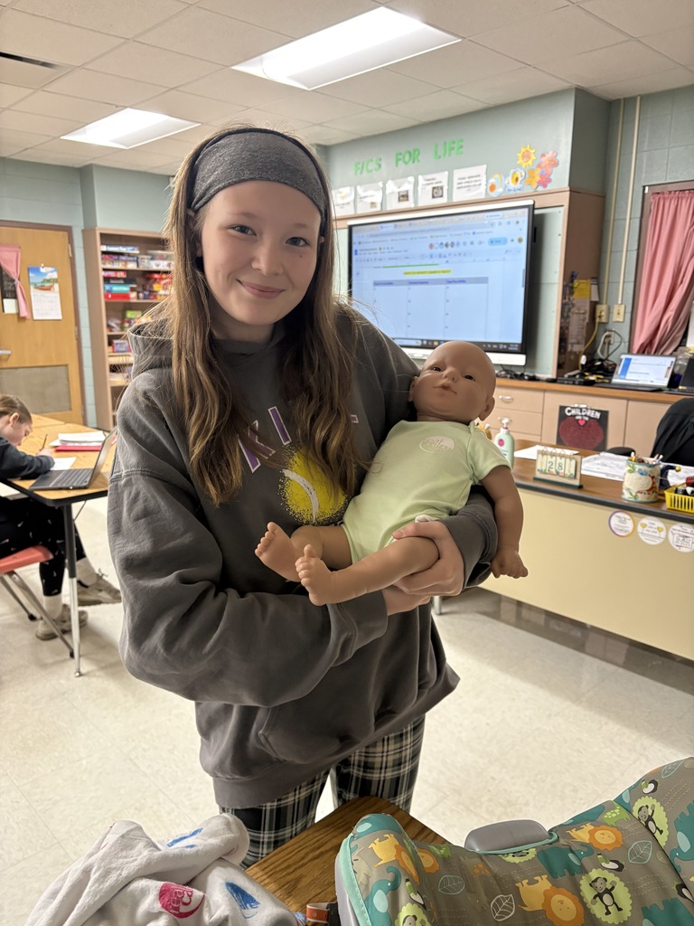 Middle school student holding a fake baby.