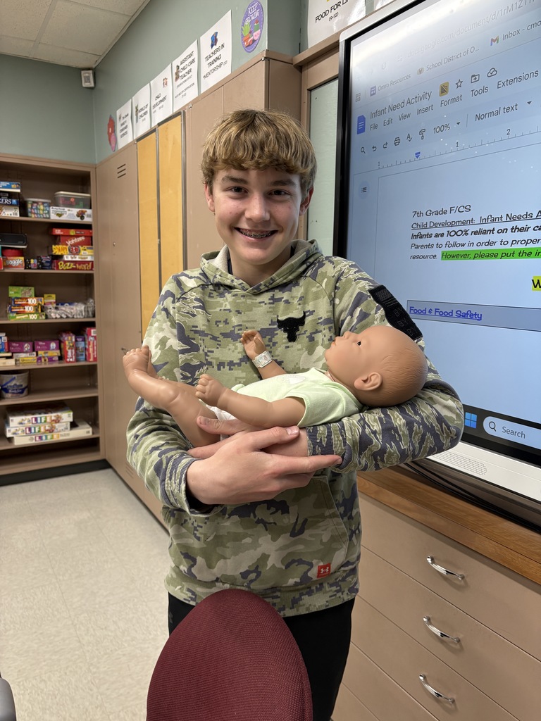 Middle school student holding a fake baby.