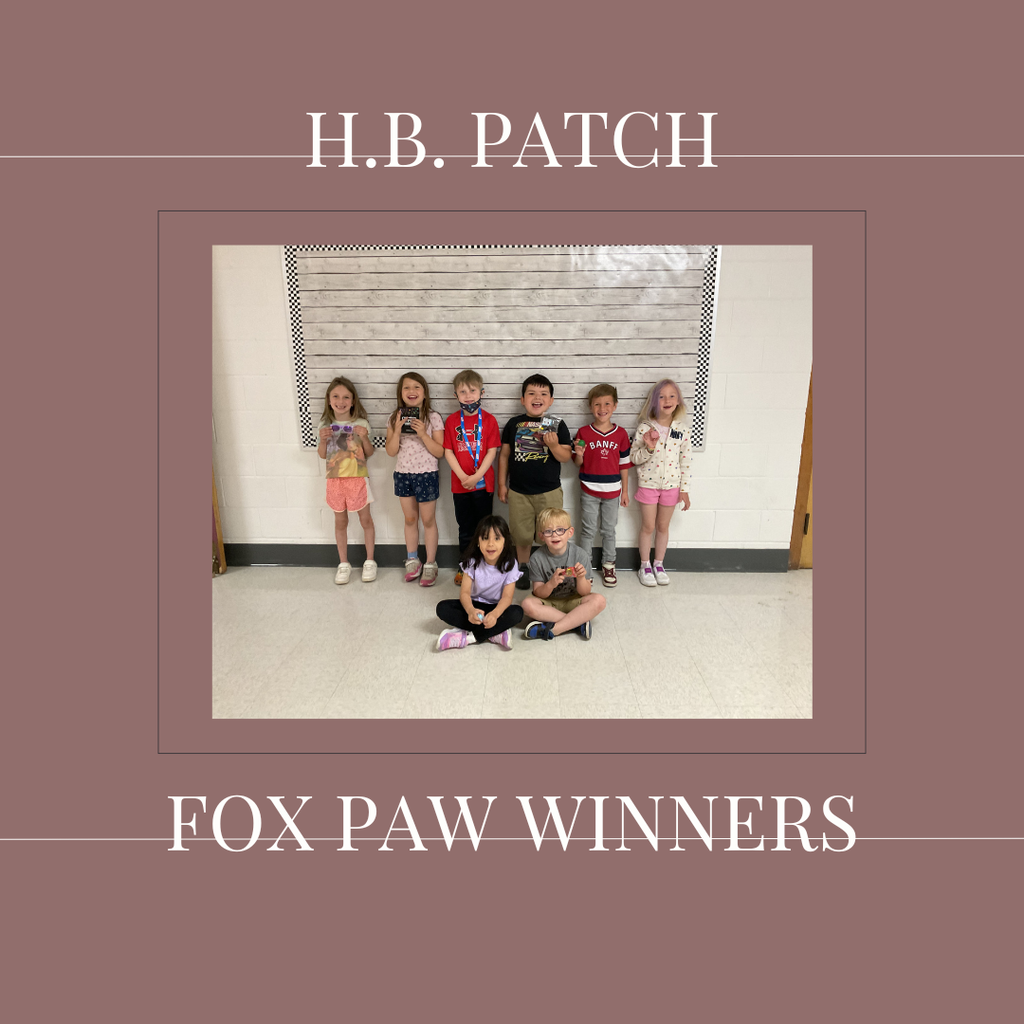 A group of early elementary students standing in front of a bulletin  board.