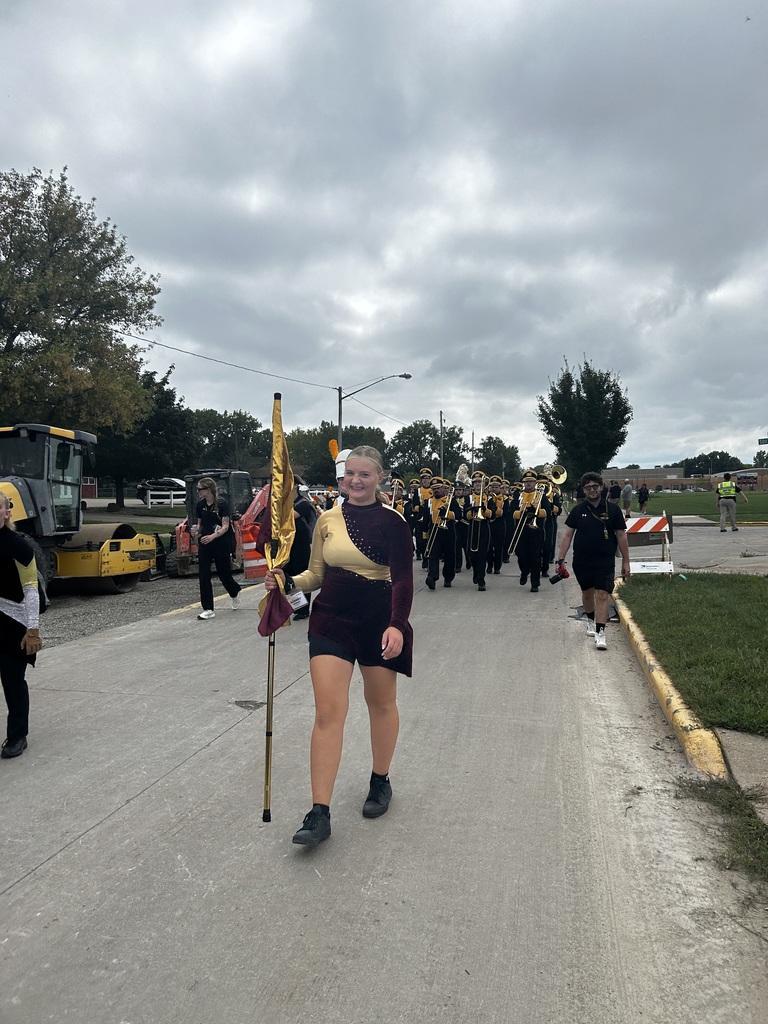 High school student carrying a color guard flag in a parade.