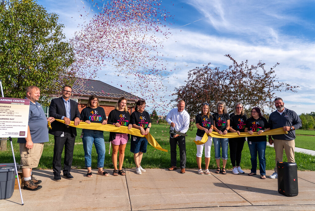 Ribbon cutting with confetti in the air.