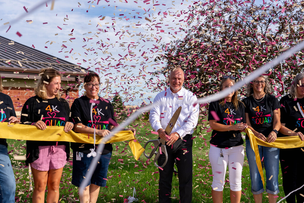 Close up of ribbon cutting with confetti in the air.