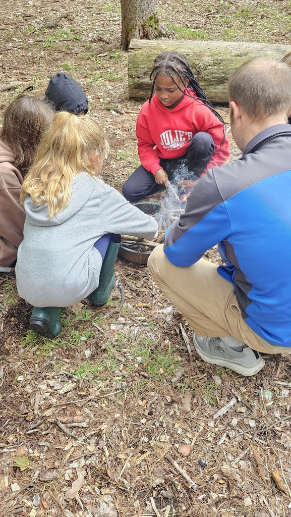 Middle school students around an outdoor fire building experience.